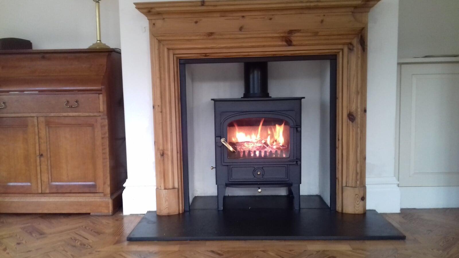 Multifuel Fuel Freestanding Stove with rendered chamber and granite slips and hearth plus wooden surround