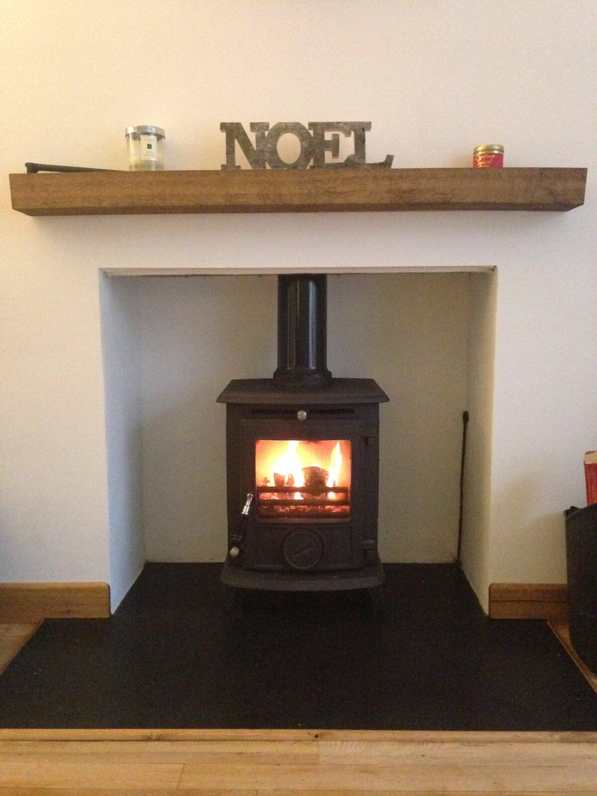 Log burning stove with rendered chamber and oak beam shelf