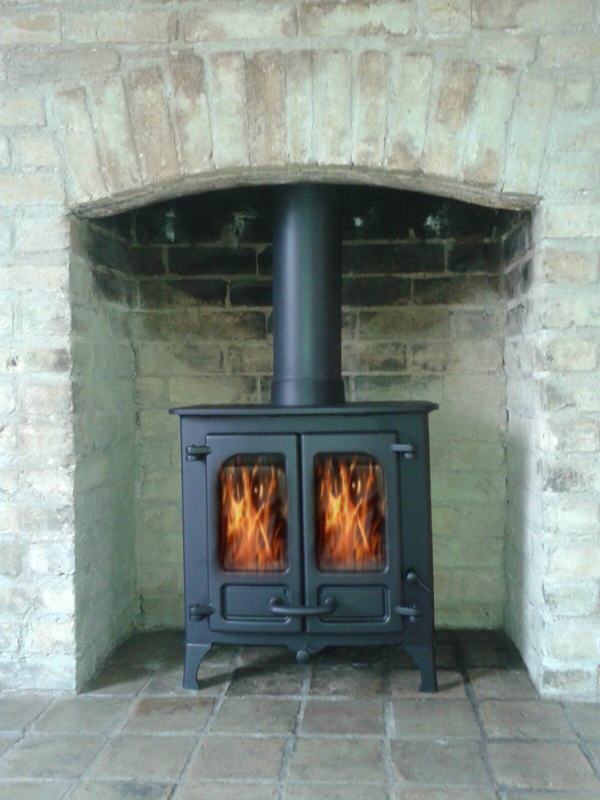Double door multifuel stove with brick chamber and stone hearth